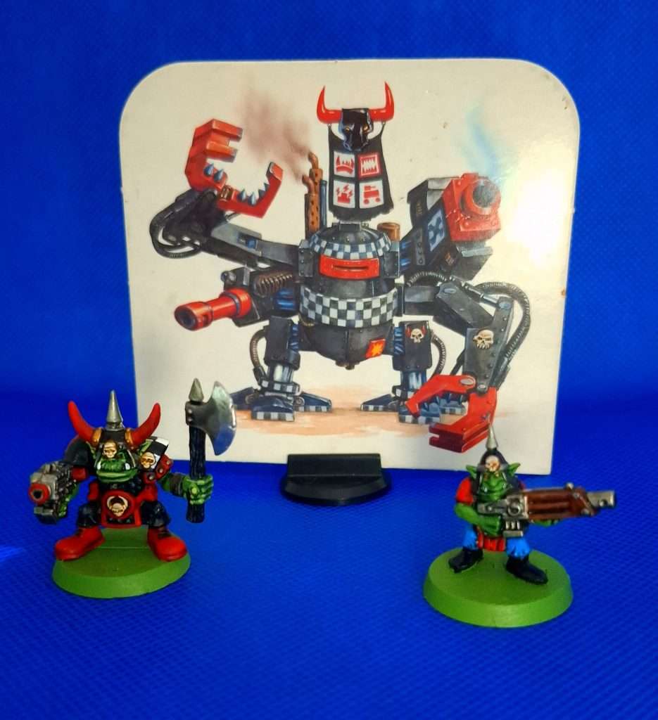 Dreadnought orko de cartón, a la izquierda un orko del clan goff, a la derecha un gretchin