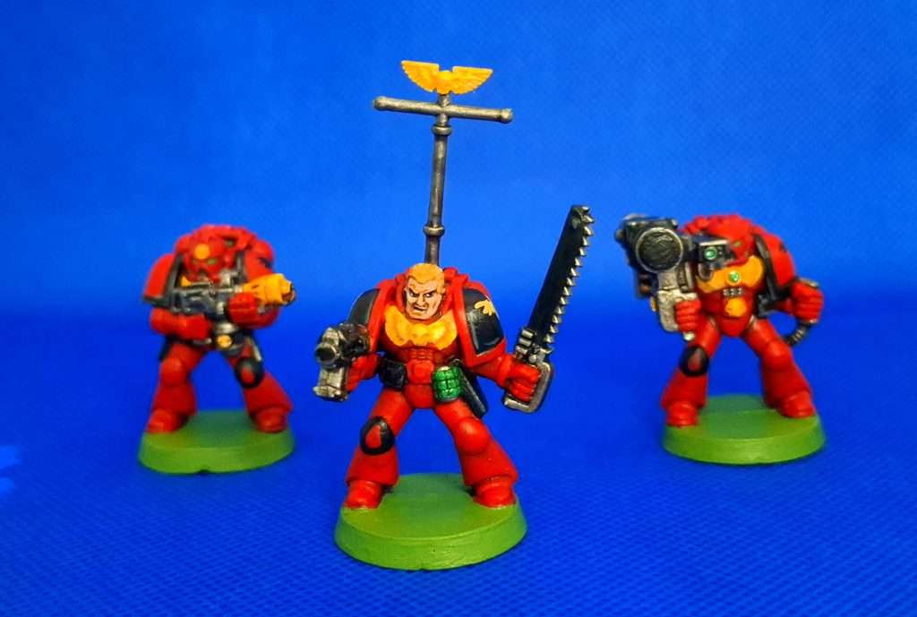 De izquierda a derecha, marine con lanzallamas, sargento marine espacial con espada sierra y marine espacial con lanzacohetes