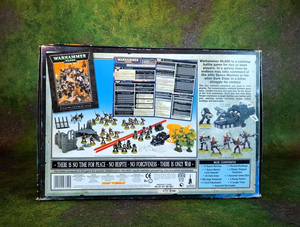 Parte de atrás de la caja de warahammer 40k, tercera edición,  a modo ilustrativo se muestra el contenido de la caja: sets de dados, reglas de juego, hojas de datos, instrumentos de medición y miniaturas.